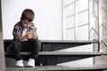 Sad little boy with mobile phone sitting on stairs Royalty Free Stock Photo