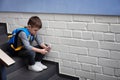 Sad little boy with mobile phone sitting on stairs Royalty Free Stock Photo