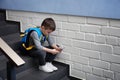 Sad little boy with mobile phone sitting on stairs Royalty Free Stock Photo