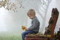 A sad little boy is sitting on a bench with his head down. Royalty Free Stock Photo