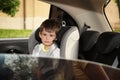 Sad little boy sitting in safety seat alone  inside car Royalty Free Stock Photo