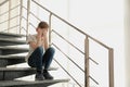Sad little boy sitting on stairs indoors Royalty Free Stock Photo