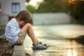 Sad little boy, sitting on the street in the rain, hugging his t Royalty Free Stock Photo