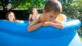 Sad little boy sitting in swimming pool with family having fun and playing Royalty Free Stock Photo