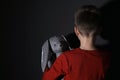 Sad little boy with toy near wall, back view. Domestic violence concept