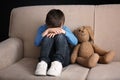 Sad little boy with toy sitting on couch Royalty Free Stock Photo