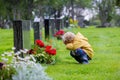 Sad little child, blond boy, standing in the rain on cemetery, sad person, mourning Royalty Free Stock Photo