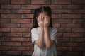 Sad little girl closing eyes with hands near wall. Child in danger Royalty Free Stock Photo