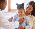 Sad little girl at doctors office. Sick girl sitting with mother while male paediatrician listen to chest heartbeat