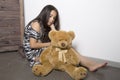 Sad little girl embracing her teddy bear. punished girl sitting near white wall Royalty Free Stock Photo