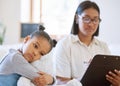 Sad little girl hugging her teddy bear while a social worker writes on a clipboard. Depressed mixed race child feeling Royalty Free Stock Photo