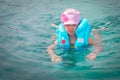 A sad little girl in a life jacket tries to swim in the ocean. Portrait of a frightened child in the sea. A baby is saved after a Royalty Free Stock Photo