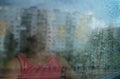 Sad Little girl pensive looking through the window glass with a lot of raindrops. Sadness and loneliness childhood concept image. Royalty Free Stock Photo