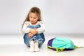 Sad little girl with school bag sitting on floor Royalty Free Stock Photo