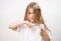 sad little girl shears long hair with scissors and afraid on a white background. Royalty Free Stock Photo