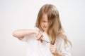 sad little girl shears long hair with scissors on a white background. Royalty Free Stock Photo