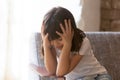 Sad little girl feel lonely sitting alone in armchair