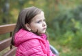 Sad little girl sitting on bench in the park at the day Royalty Free Stock Photo