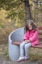 Sad little girl sitting on bench in the park Royalty Free Stock Photo