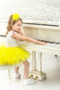 Sad little girl sitting leaning on a white Grand piano. Royalty Free Stock Photo