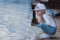 Sad little girl sitting on a pier and looks at river Royalty Free Stock Photo