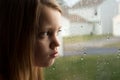 Sad little girl staring out rainy window Royalty Free Stock Photo