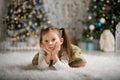 Sad little girl with two tails on a white carpet. New Year photo session