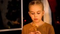 Sad little girl waiting for parents near orphan home window, eating Xmas cookie Royalty Free Stock Photo