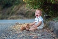 Sad little toddler boy, holding teddy bear, sitting lonely on a road in park, crying with sadness