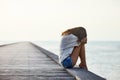 Sad lonely beautiful woman sitting on the pier