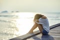 Sad lonely beautiful woman sitting on the pier