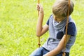 Sad lonely boy sitting on swings. Close up.