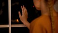 Sad lonely girl looking through window, waiting parents in orphan home, adoption