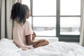 Sad lonely girl sitting on the bed and looking at the window Royalty Free Stock Photo