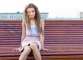 Sad lonely girl sitting on a bench a warm summer day in the city Royalty Free Stock Photo