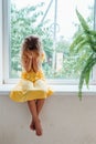 Sad lonely little girl sitting on windowsill crying and covering eyes with hands Royalty Free Stock Photo