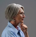 Sad lonely mature woman. Senior woman thinking in low light. Grey haired mature woman studio shot in low light. Dramatic