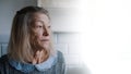 Sad lonely old gray haired woman looking through the window. Vulnerable person in quarantine Royalty Free Stock Photo