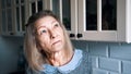 Sad lonely old gray haired woman looking through the window. Vulnerable person in quarantine Royalty Free Stock Photo