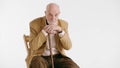 Sad lonely old man sitting in an armchair with cane isolated on white background Royalty Free Stock Photo