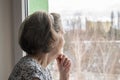 Sad lonely old woman look next to window allone depressed abandoned