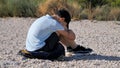 Sad, lonely, unhappy, disappointed child sitting alone on the ground. Outdoors Royalty Free Stock Photo