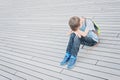 Sad, lonely, unhappy, disappointed child sitting alone on the ground outdoors Royalty Free Stock Photo