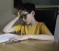 Sad looking boy doing homework during quarantine time