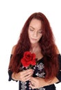 Woman with red hair looking down on her red rose Royalty Free Stock Photo