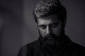 Sad man boy portrait. upset person looking down. hopeless situation. black and white single light. beard indian young handsome guy Royalty Free Stock Photo