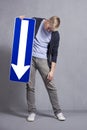 Sad man holding direction arrow sign pointing down.