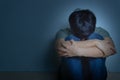 sad man hug his knee and cry sitting alone in a dark room. Depression, unhappy, stressed and anxiety disorder concept Royalty Free Stock Photo