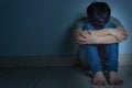 Sad man hug his knee and cry sitting alone in a dark room. Depression, unhappy, stressed and anxiety disorder concept Royalty Free Stock Photo