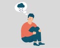 Sad man hugs his knees with rainy cloud above his. Unhappy boy sits on the floor and looks stressed and depressed. Royalty Free Stock Photo